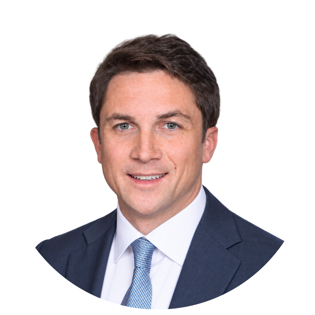 Man in a navy suit and light blue tie, smiling, with short brown hair, shown against a plain white background in a circular frame—an ideal look for Novi Calgary Connect 2026.